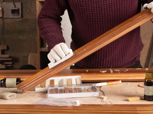 muž aplikuje olej na drevenú dosku handričkou